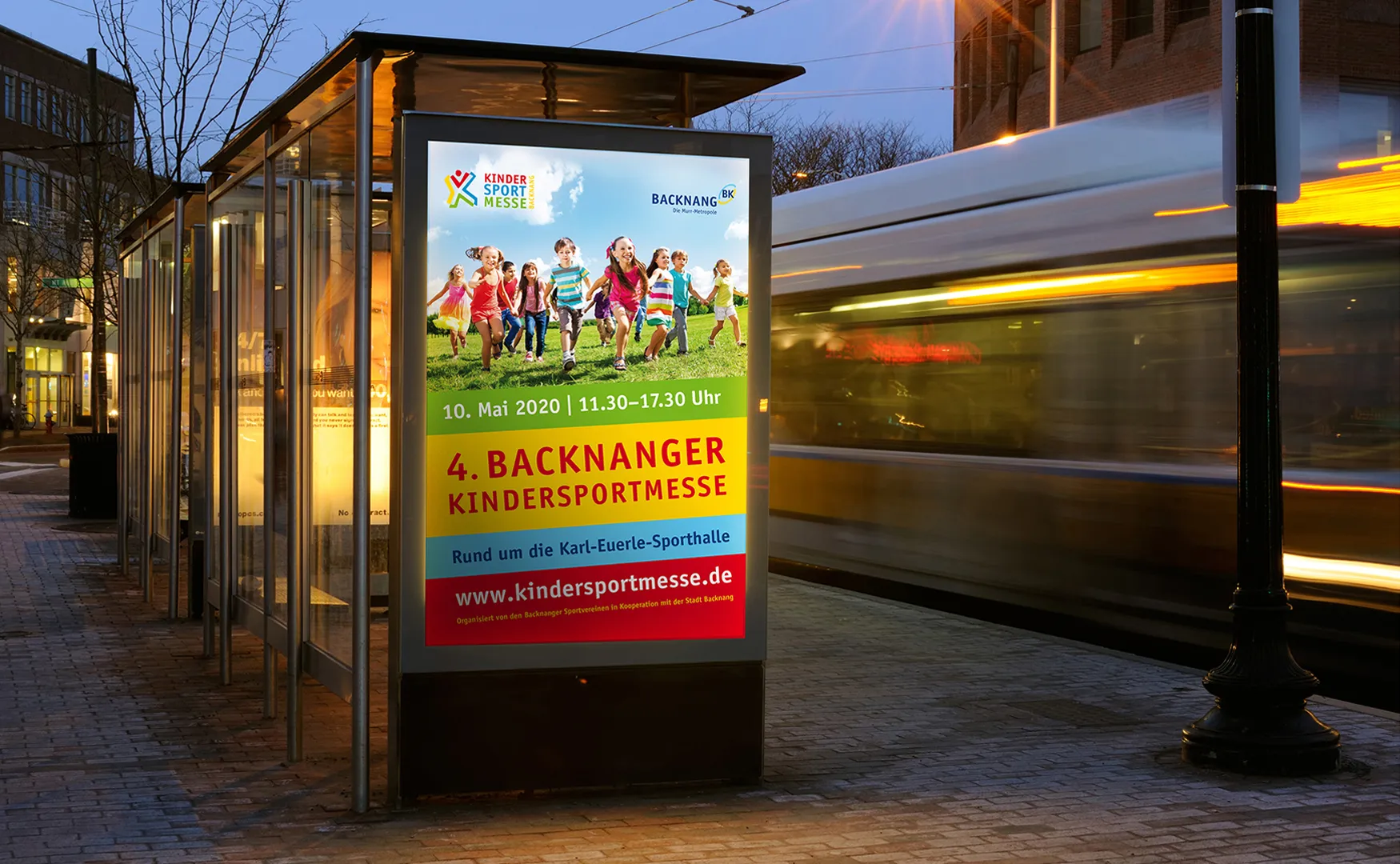 Citylight-Plakat der Kindersportmesse Backnang in einer beleuchteten Haltestelle am Abend