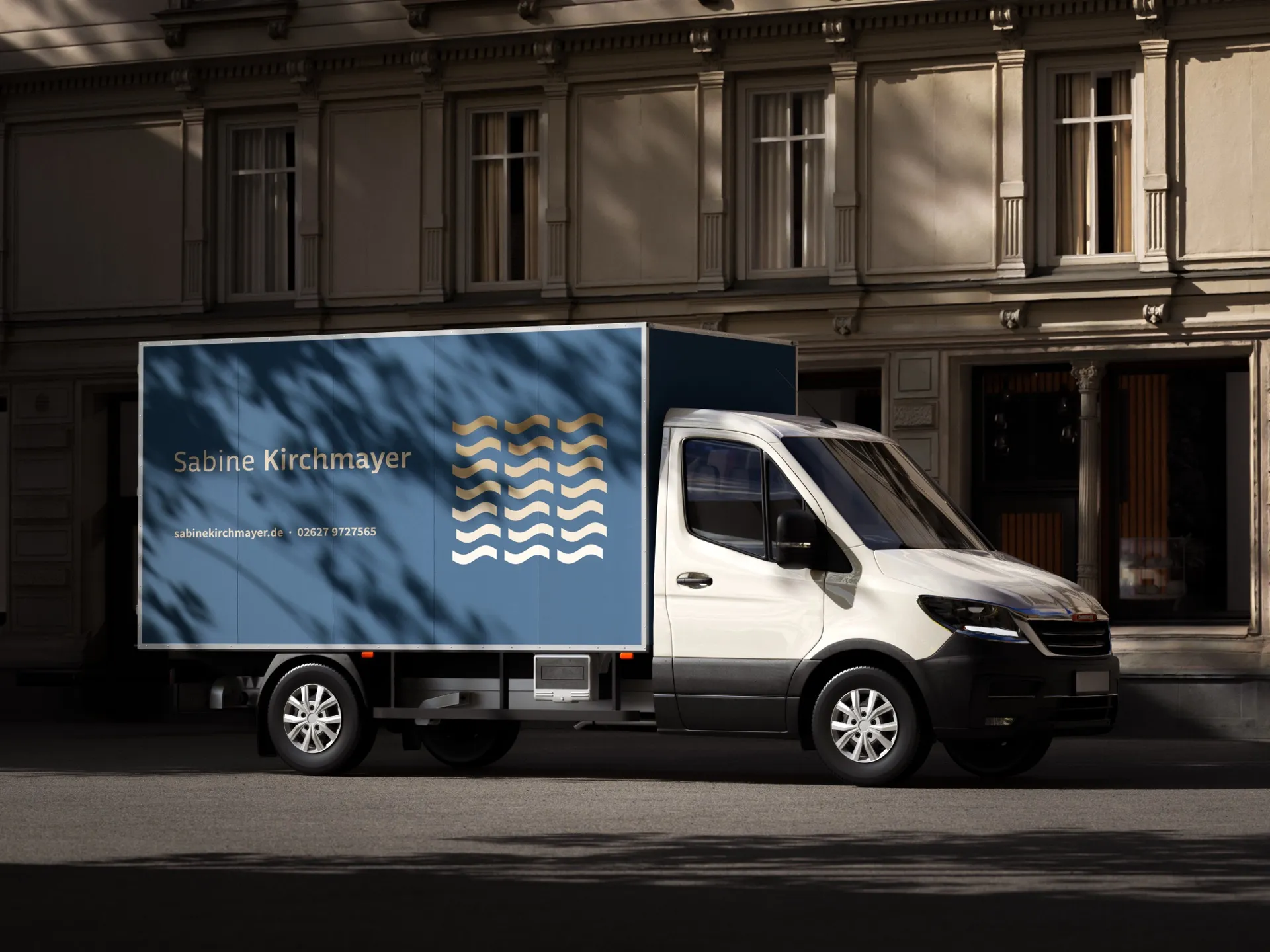 Kastenwagen mit blau beklebtem Kofferaufbau, Namenszug, Wellengrafik und Kontaktdaten