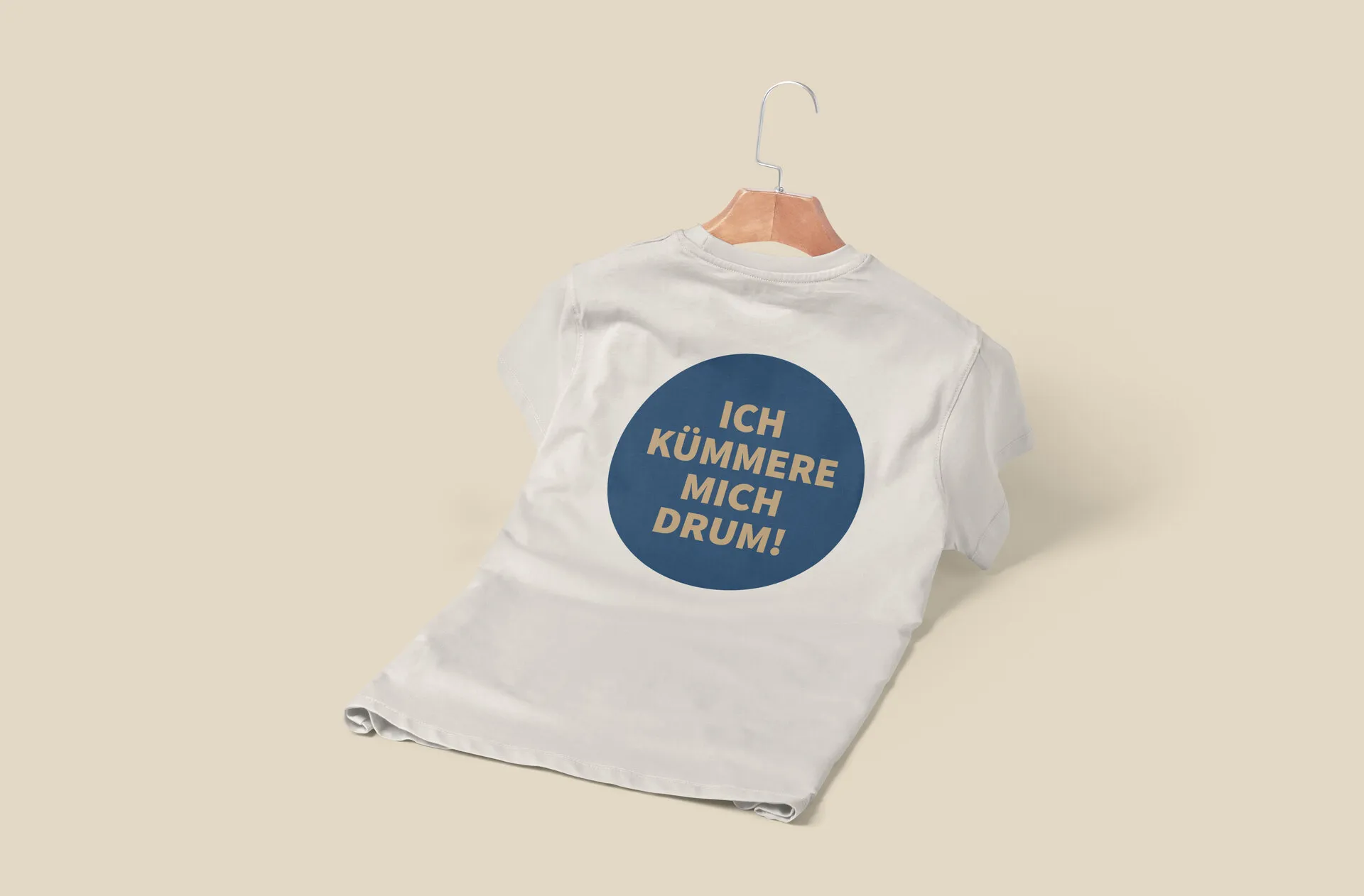Cremefarbenes T-Shirt von hinten mit großem Rückendruck „Ich kümmere mich drum!“ in einem blauen Kreis