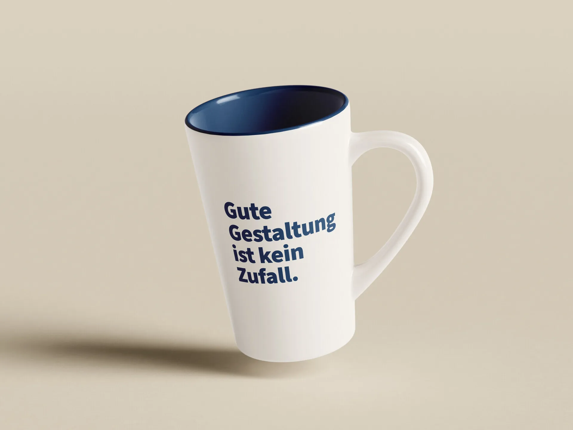 Weiße Tasse mit blauer Innenseite und dem Aufdruck „Gute Gestaltung ist kein Zufall.“